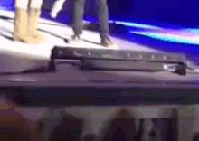 a group of people are standing on a stage with a suitcase in the foreground
