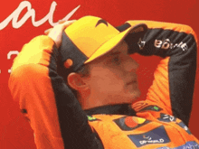 a man wearing an orange shirt and a yellow hat holds his hands to his head