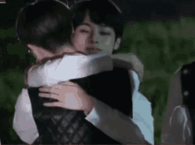 a man and a woman are hugging each other in a field .