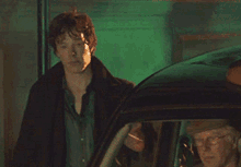 a man standing next to a car talking to another man