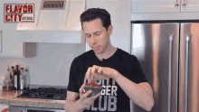 a man in a flavor city shirt holds a bowl