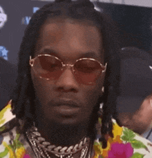 a close up of a man wearing sunglasses and a flowered shirt .