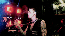 a man with a tattoo on his arm is smoking a cigarette on stage