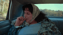 a woman with a scarf around her head is sitting in a car