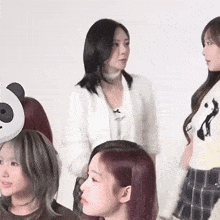 a woman wearing a panda mask stands next to a group of women