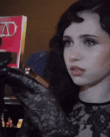 a woman in a black lace top is holding a red book that says ad on it
