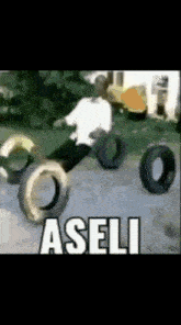 a man is playing with tires and the word aseli is on the ground