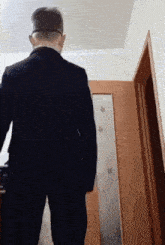 a man in a suit is standing in front of a door with arrows on it