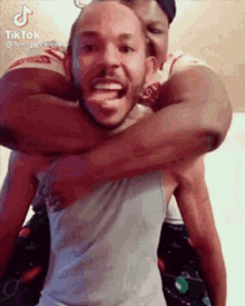a man is carrying another man on his shoulders and they are hugging each other .