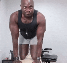 a man in a black tank top and grey shorts is doing push ups on his knees