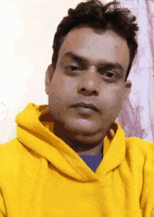 a man wearing a yellow hoodie is taking a selfie with kinemaster