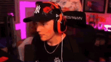 a man wearing a baseball cap and headphones is sitting in a chair in front of a microphone .