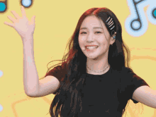 a girl waves her hand in front of a yellow background