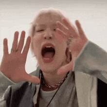 a person with their mouth open making a funny face with their hands