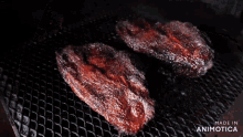 two pieces of meat are cooking on a grill and the words made in animotica can be seen in the corner
