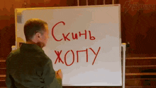 a man stands in front of a whiteboard that says " skinb xopy " in red marker