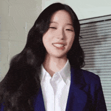a woman in a blue suit and white shirt is smiling .