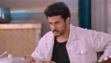 a man in a white jacket is sitting at a table eating food