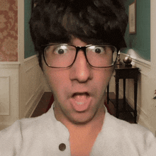 a man wearing glasses and a white shirt makes a surprised face