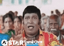 a man stands in front of a crowd with a star tamil chat logo