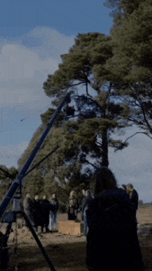 a group of people are standing in front of a crane with trees in the background