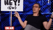 a man sitting in front of a sign that says hey ( ew )