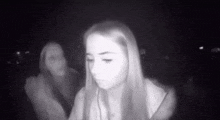 a woman is sitting in a dark room with a ghost in the background .