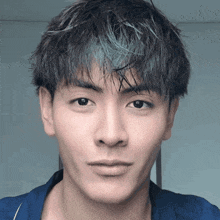 a close up of a young man 's face with a blue shirt on