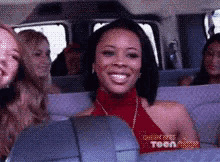 a woman in a red top is smiling while sitting in a van