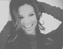 a woman is smiling with her hand in her hair