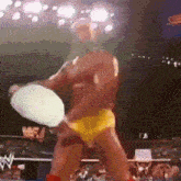 a man in a yellow underwear is holding a pizza in his hand .