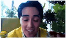 a man in a yellow shirt is smiling with mayward written on the bottom right