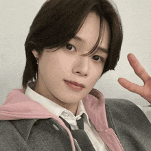 a close up of a person 's face with their hand making a peace sign