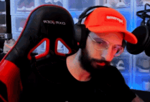 a man with a beard wearing an orange hat that says supreme
