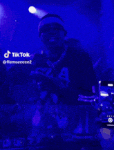 a tiktok video of a man singing in front of a blue background