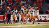 a group of football players are on a field with a referee and a sign that says r on it
