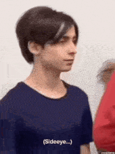 a young man in a blue shirt is standing next to a woman in a red shirt and talking to her .