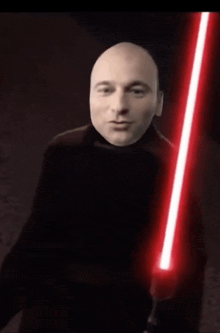a bald man is holding a red light saber in his hand