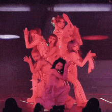 a group of women are dancing on a stage with purple lights behind them