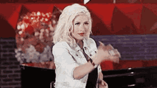 a woman in a white denim jacket is sitting in a chair and making a funny face .