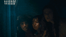 a group of people are standing in a dark room and looking at something