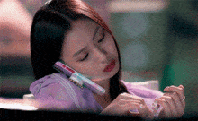a woman in a purple shirt is talking on a phone