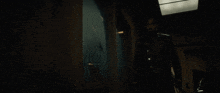 a man in a black suit walks down a hallway