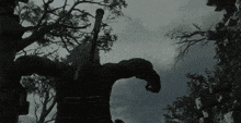 a statue of a man with a sword in his hand is surrounded by trees