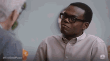 a man wearing glasses is sitting in front of another man .