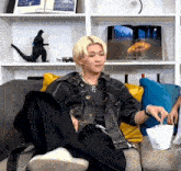 a man is sitting on a couch with his feet up and eating popcorn .