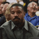 a man with a beard is sitting in a crowd at a basketball game .