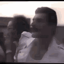a man in a white shirt is talking on a cell phone in a crowd .