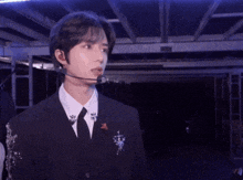 a young man wearing a suit and tie with a microphone on his head