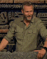 a man in a green shirt is looking at his watch